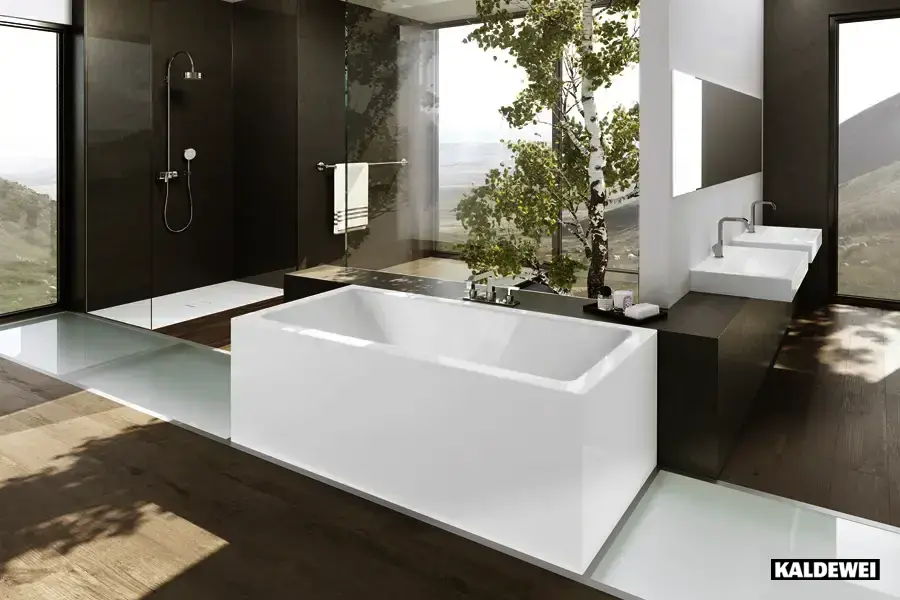 Freistehende weiße Badewanne von Kaldewei in dunklem Designbad mit Panoramafenster und Naturblick – Wellnessoase von Der Bäderbauer